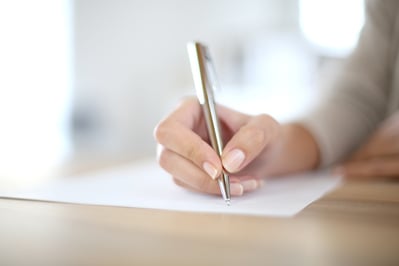 Closeup of woman's hand writing on paper