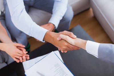 Salesman shaking hands with client with contract on the coffee table Salesman shaking hands with client with contract on the coffee table